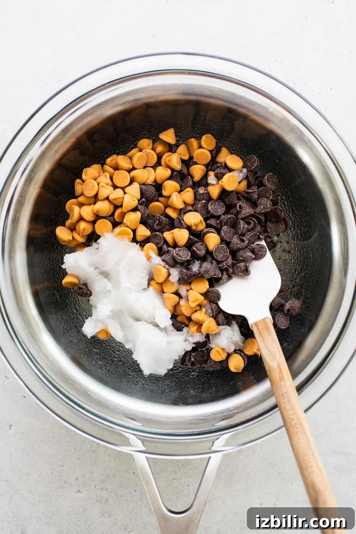 Chocolate chips in a bowl with a wooden spoon.