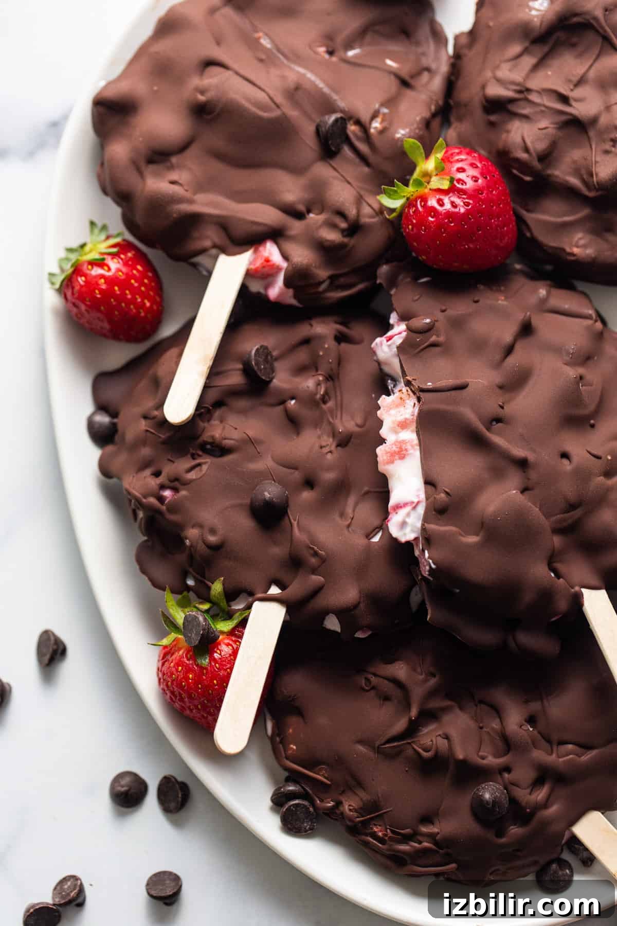 Chocolate-Dipped Strawberry Frozen Yogurt Bars 2 Chocolate covered strawberry popsicles on a plate.