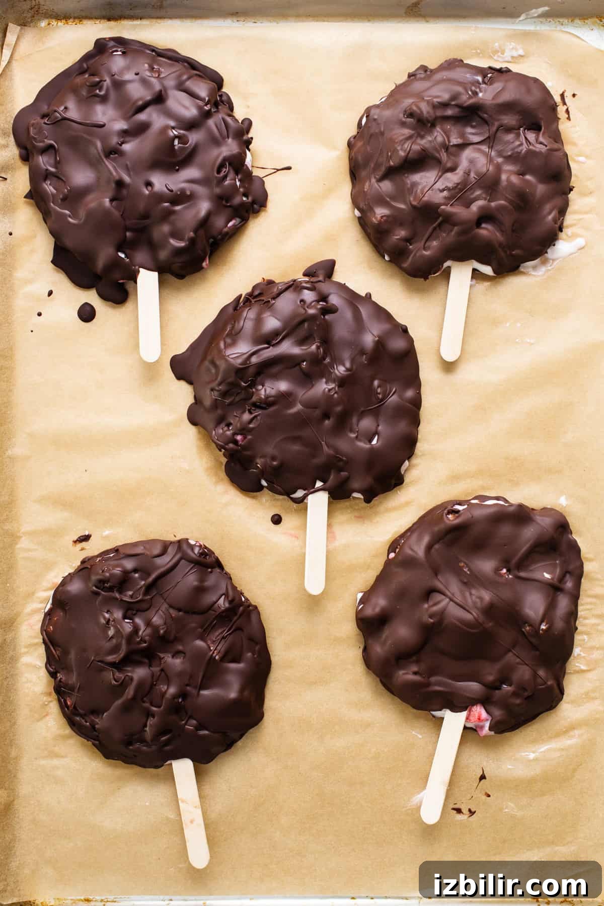Chocolate-Dipped Strawberry Frozen Yogurt Bars 5 Chocolate covered popsicles on a baking sheet.