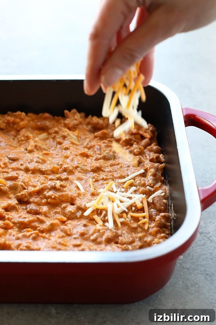 Sprinkling cheese on chili cheese dip sprinkling cheese on bean dip