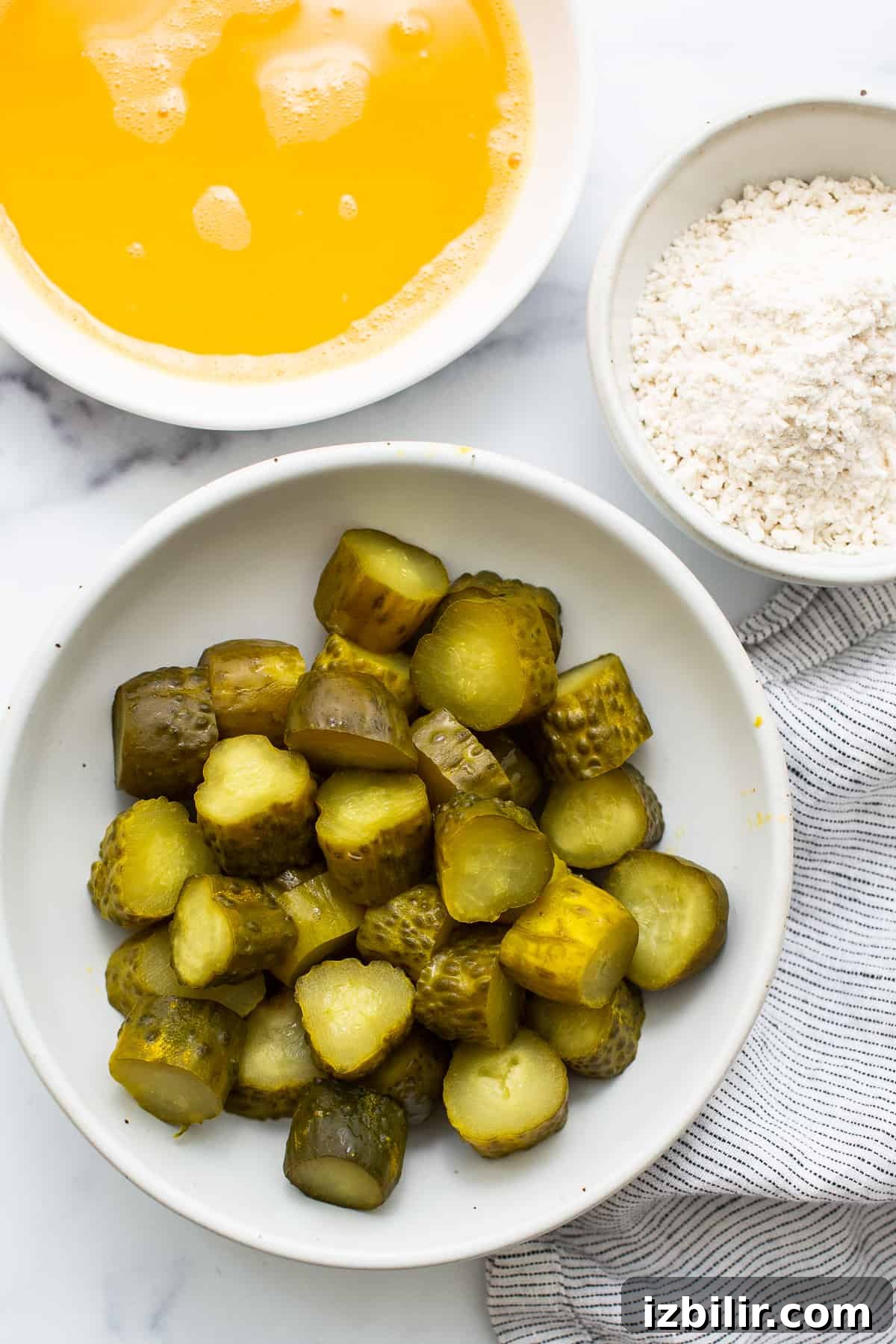 Crispy Air Fryer Pickle Chips Recipe 4 A bowl of pickles next to a bowl of flour.