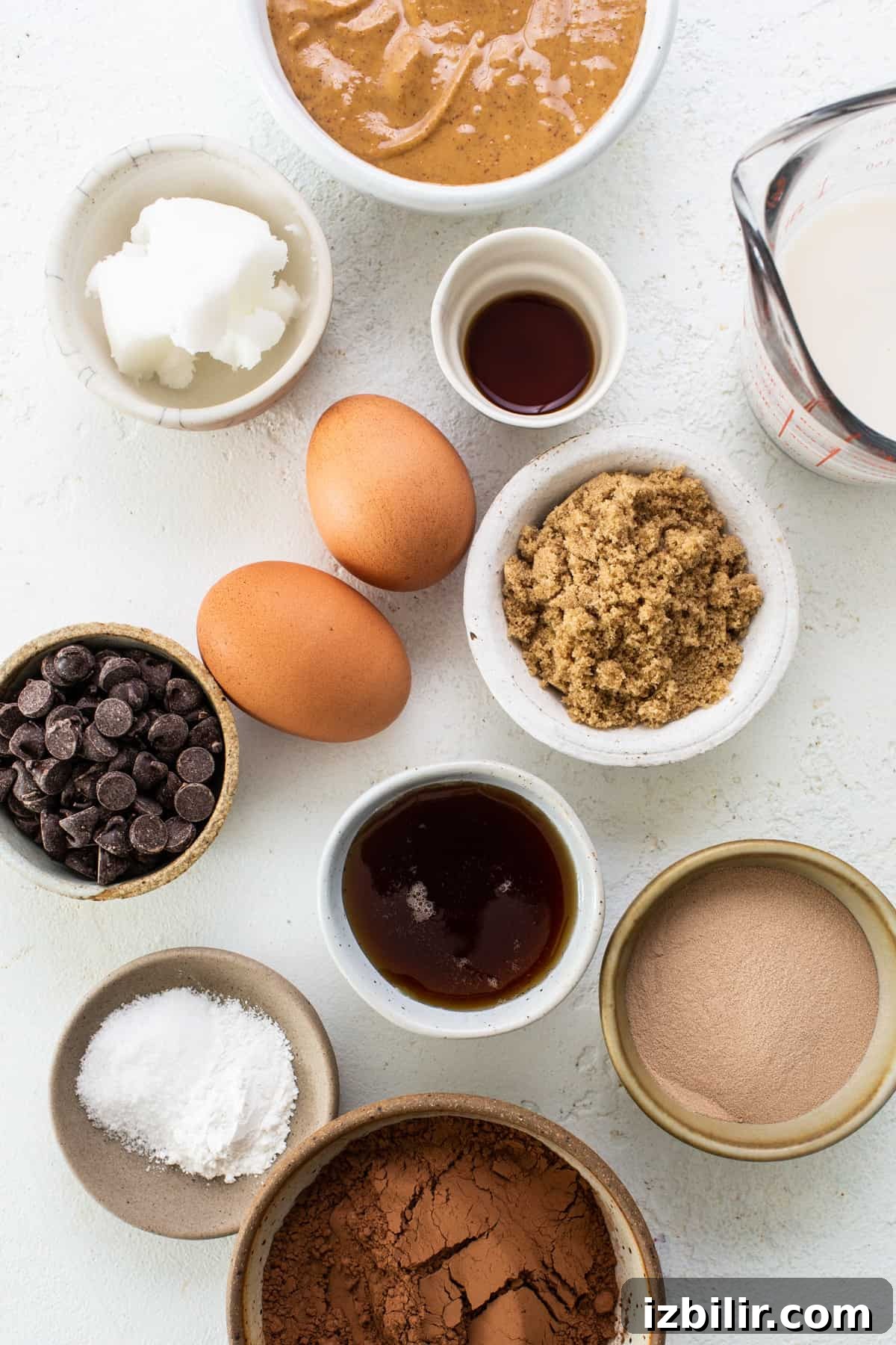 Flourless Peanut Butter Protein Brownies Recipe 3 The ingredients for a chocolate cake are shown in bowls on a white background.