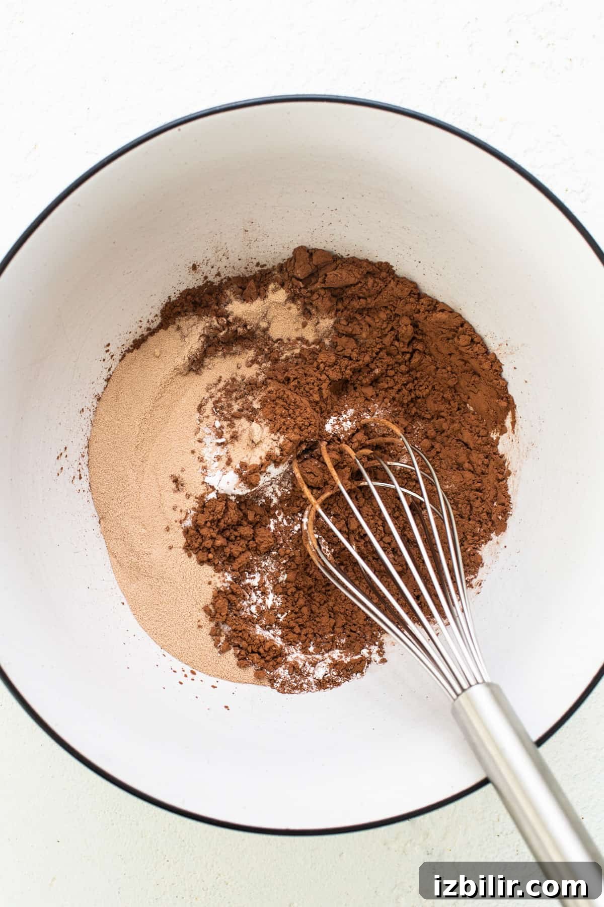 Flourless Peanut Butter Protein Brownies Recipe 4 A bowl with cocoa powder and a whisk.