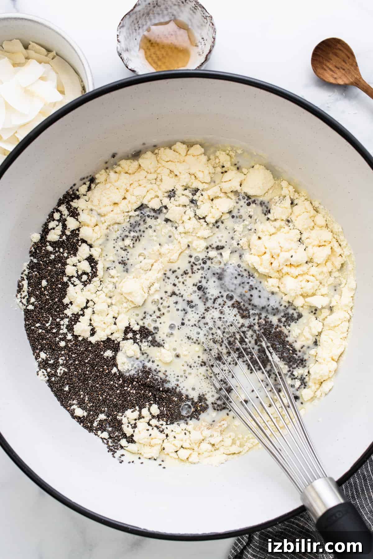 Coconut Cream Pie Chia Pudding Cups with Protein 5 A bowl of ingredients in a pan with a wooden spoon.