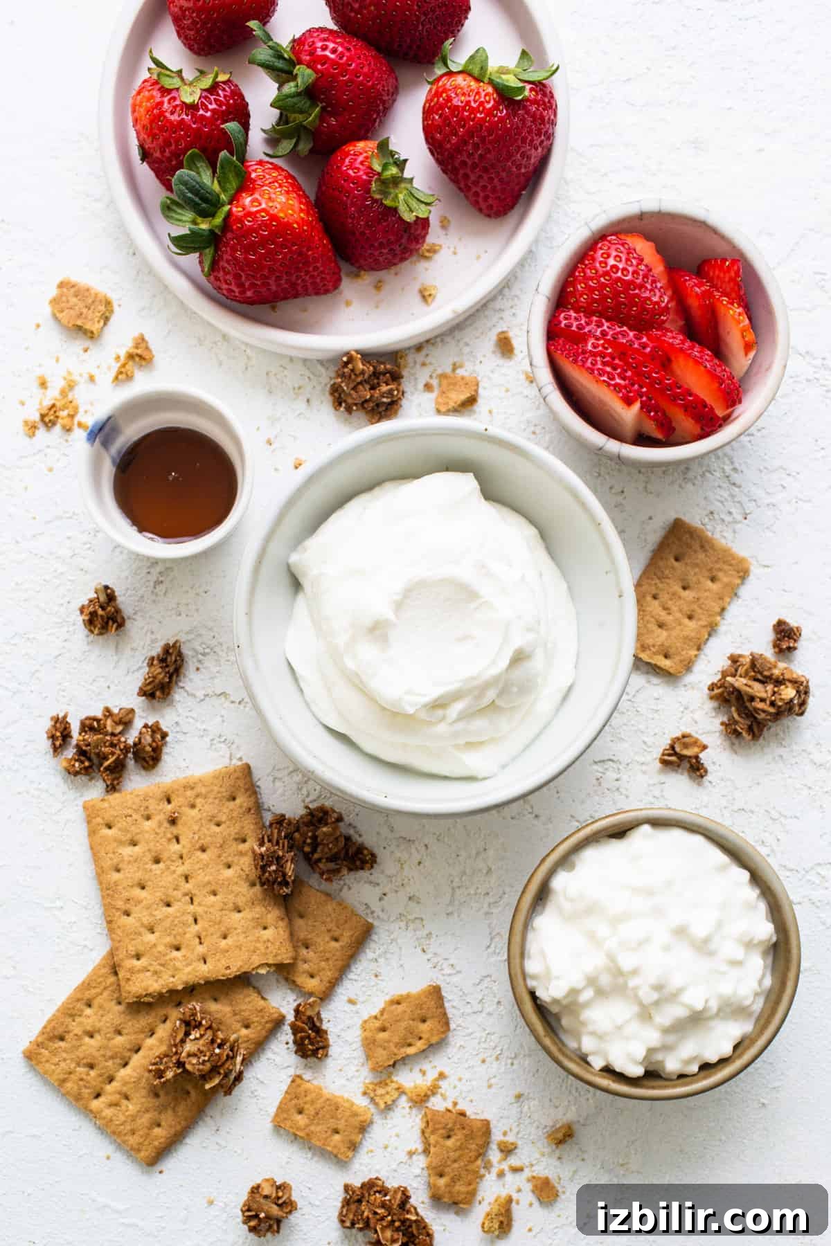 Strawberry Protein Cheesecake Jars with Cottage Cheese 4 Strawberries, graham crackers and whipped cream on a white background.