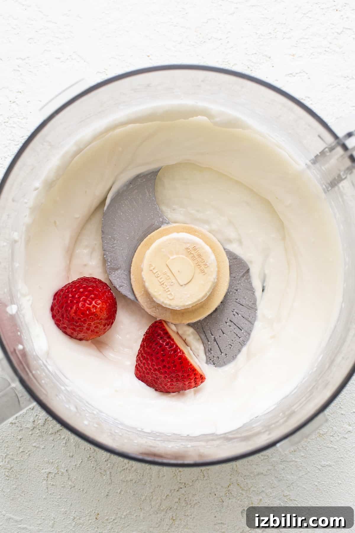 Strawberry Protein Cheesecake Jars with Cottage Cheese 5 A food processor with whipped cream and strawberries.