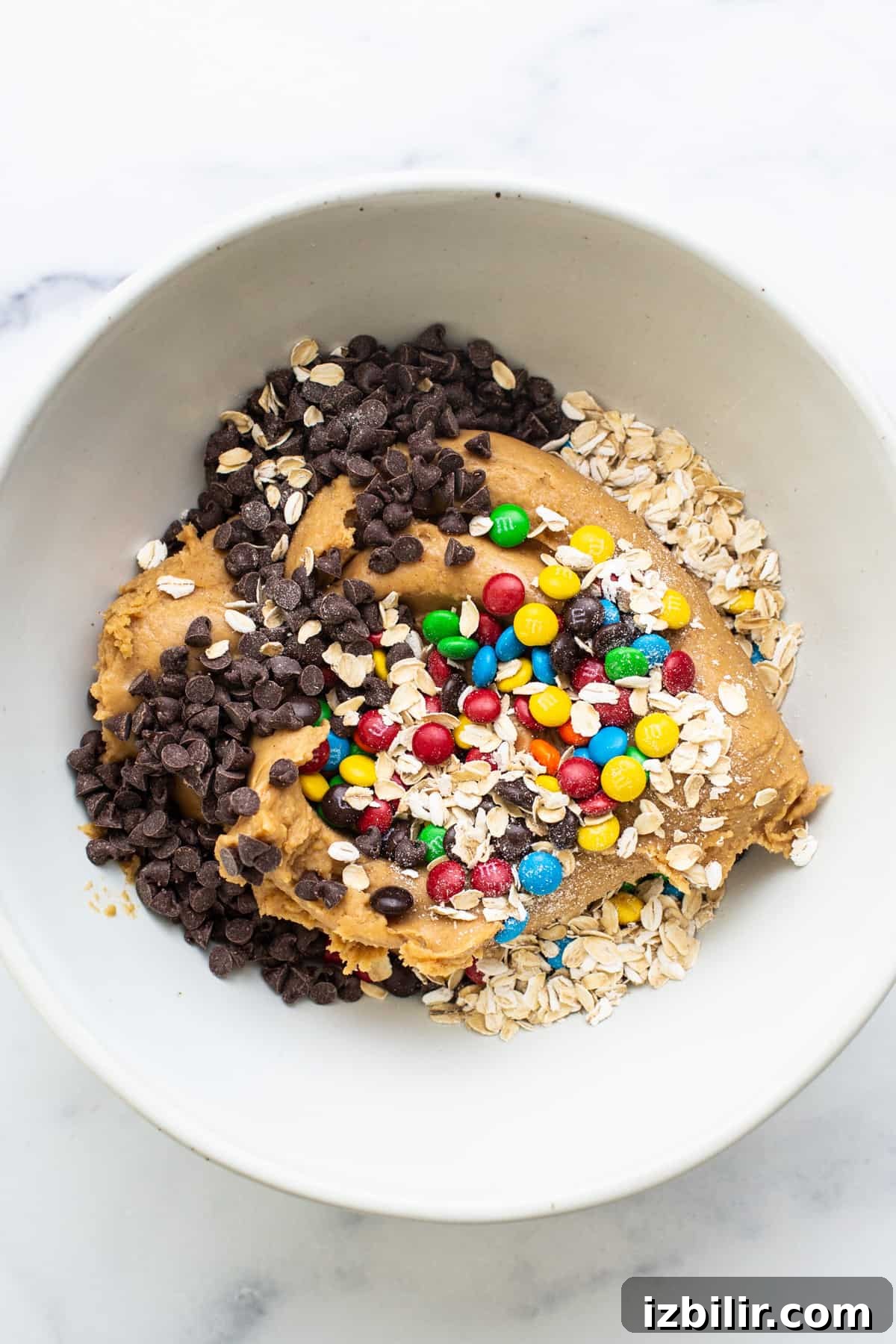 A white bowl filled with granola, oats and chocolate chips.