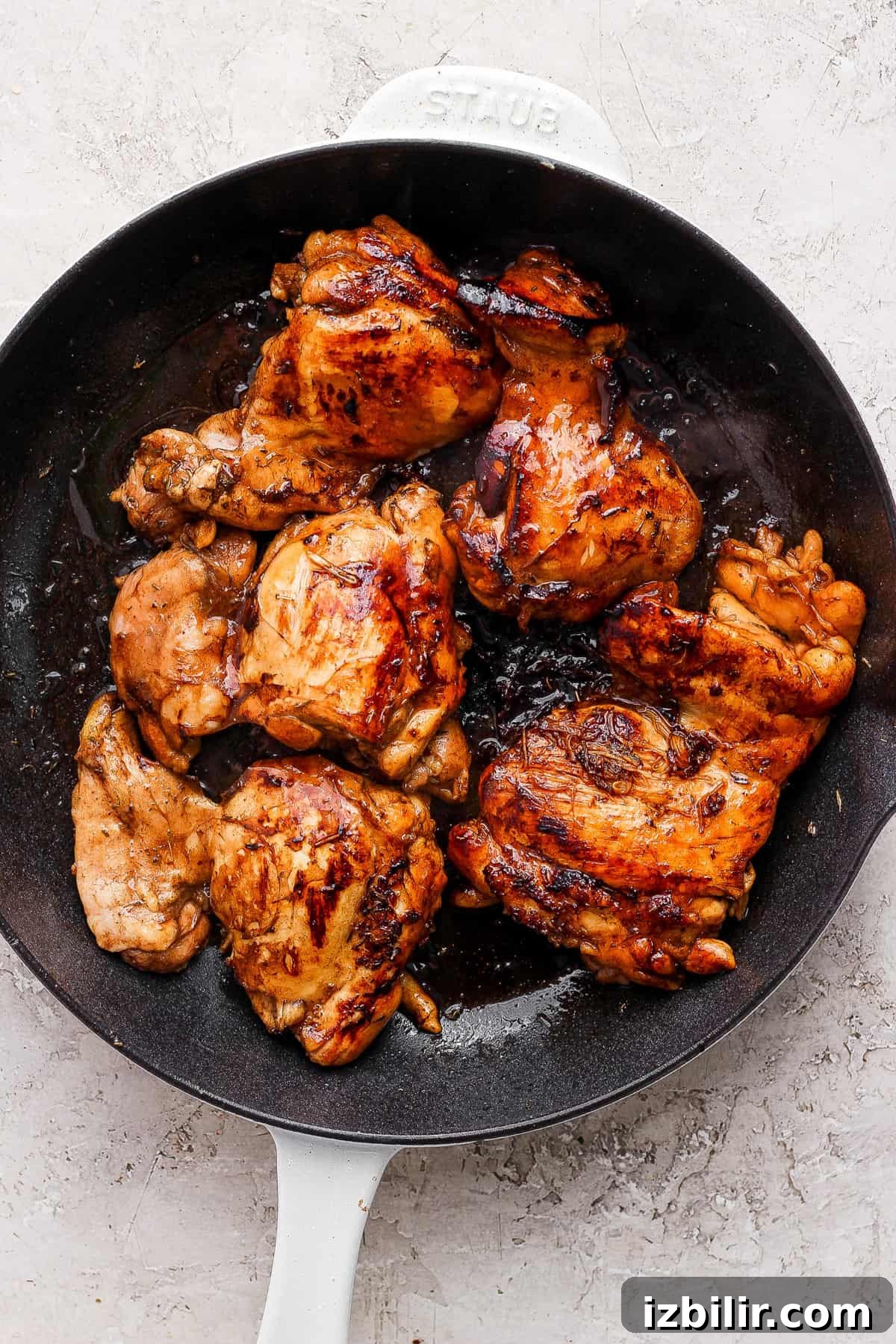 Sticky Balsamic Chicken Thighs with Garlic 3 Grilled chicken in a skillet on a white background.