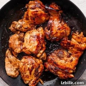 Sticky Balsamic Chicken Thighs with Garlic 6 Grilled chicken in a skillet on a white background.