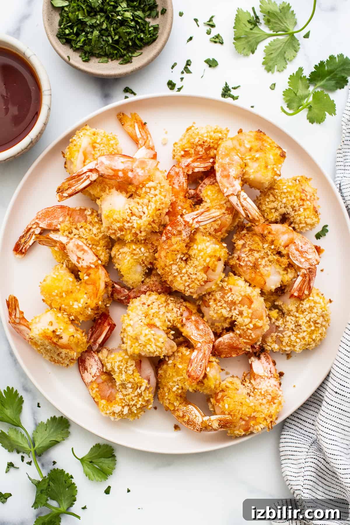 Fried shrimp on a plate with herbs and sauce.