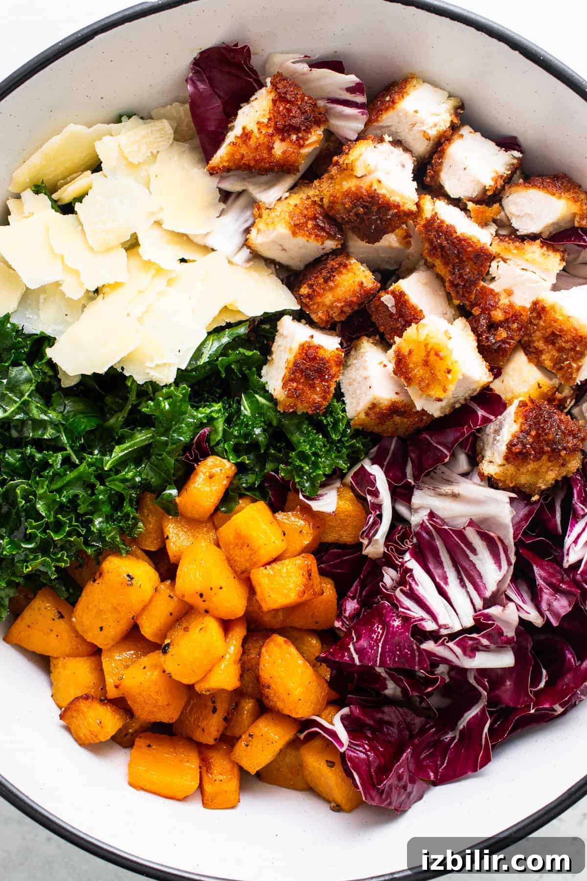 A bowl with chicken, kale, and parmesan.