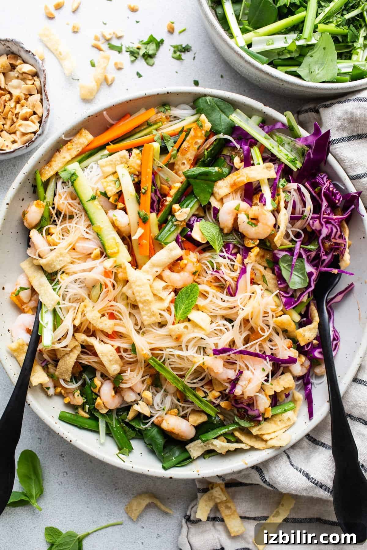 A bowl of asian noodle salad with peanuts and vegetables.