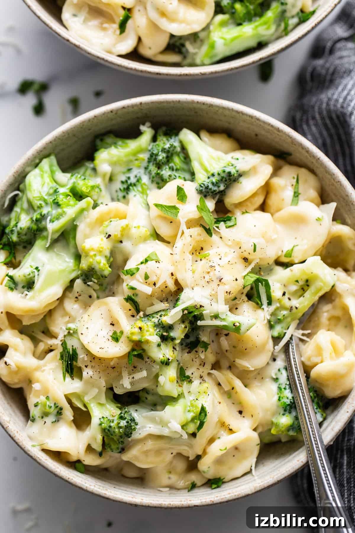 Two bowls of pasta with broccoli and parmesan cheese.