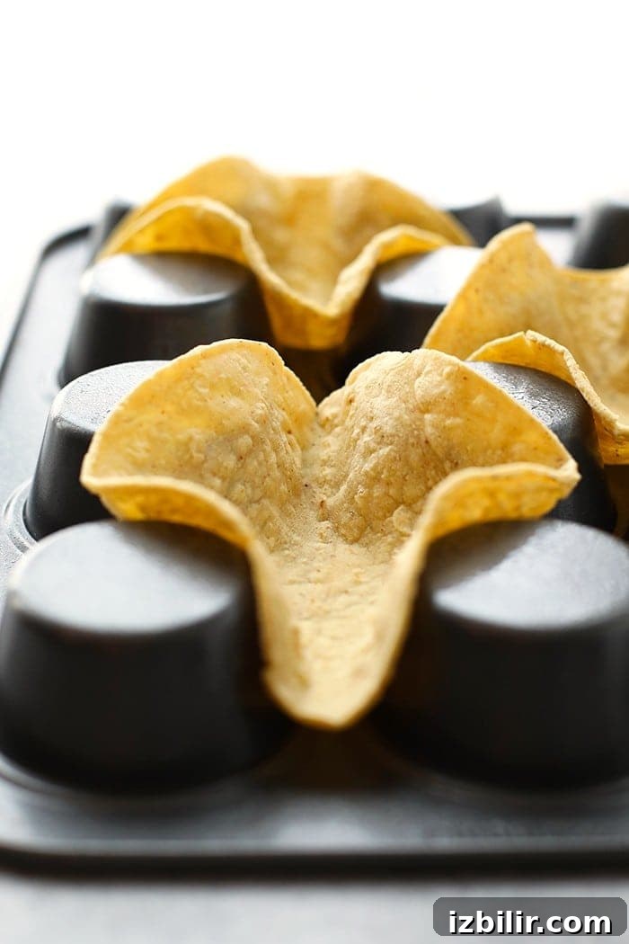Taco night just got a whole lot cuter! Get the whole family involved and make these adorable mini taco cups made with homemade hard shell taco boats. Taco shells in an upside down muffin tin.