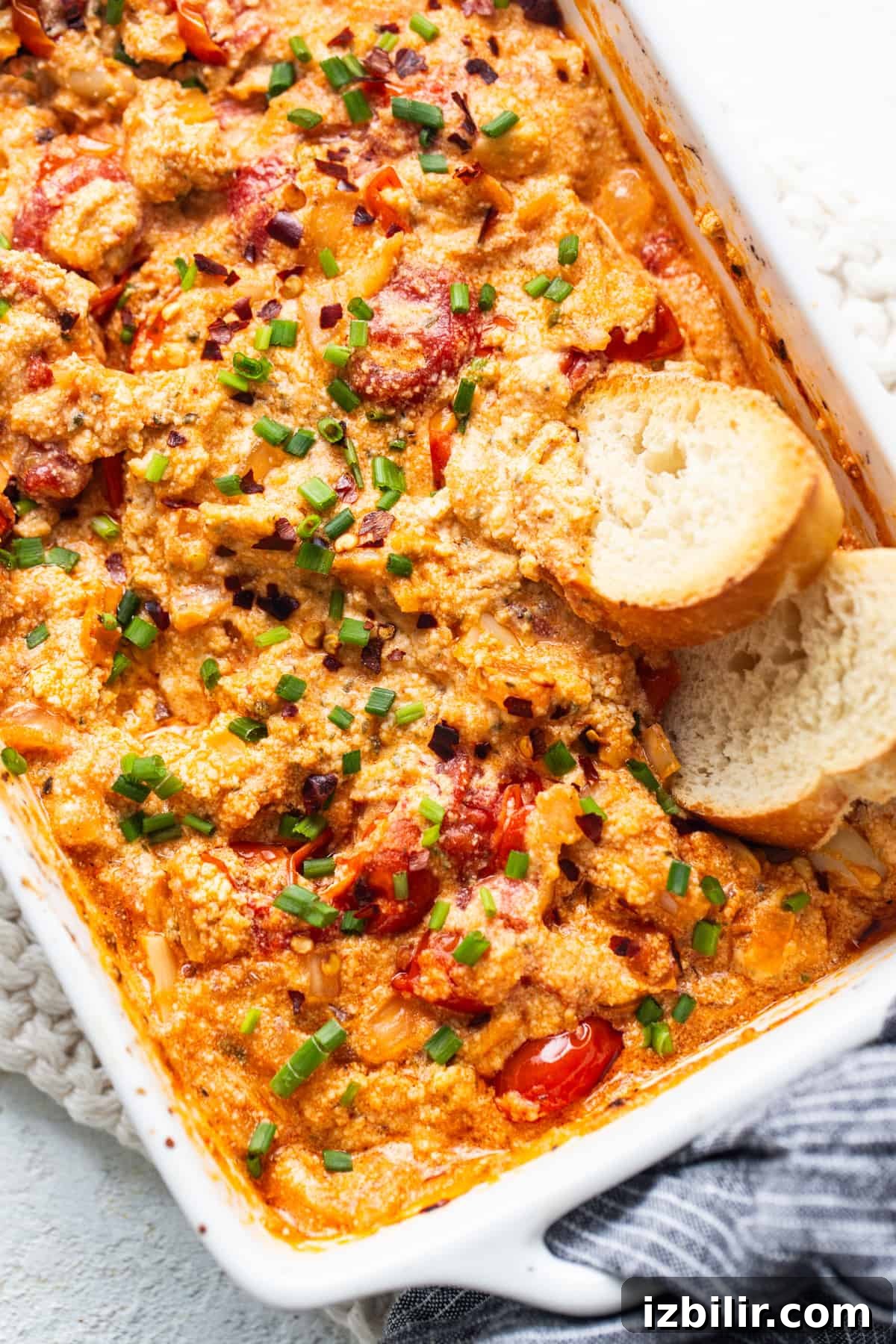 A casserole dish with chicken, tomatoes and bread.