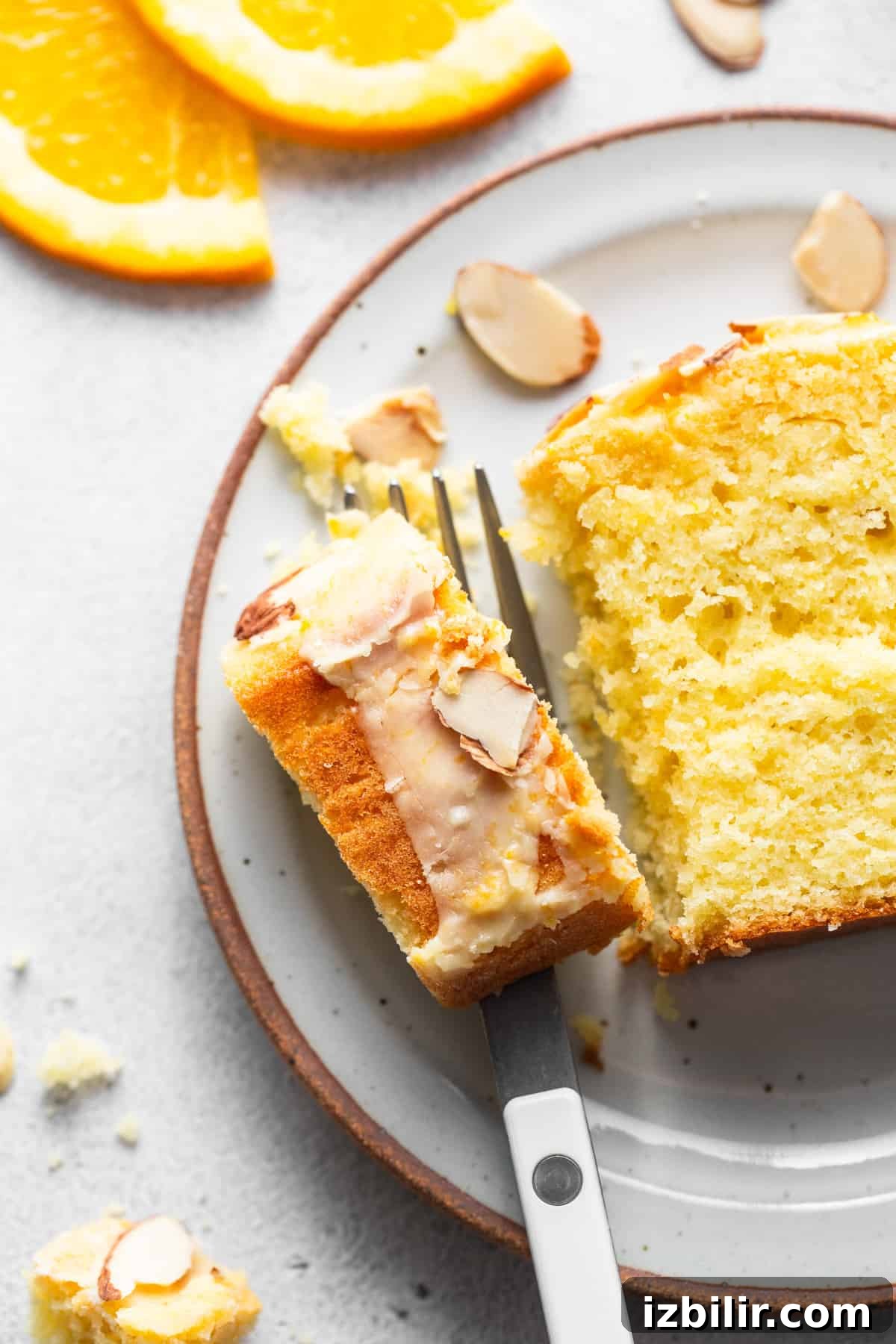 Zesty Orange Cake Recipe with Citrus Glaze 7 A slice of orange cake with almonds on a plate.