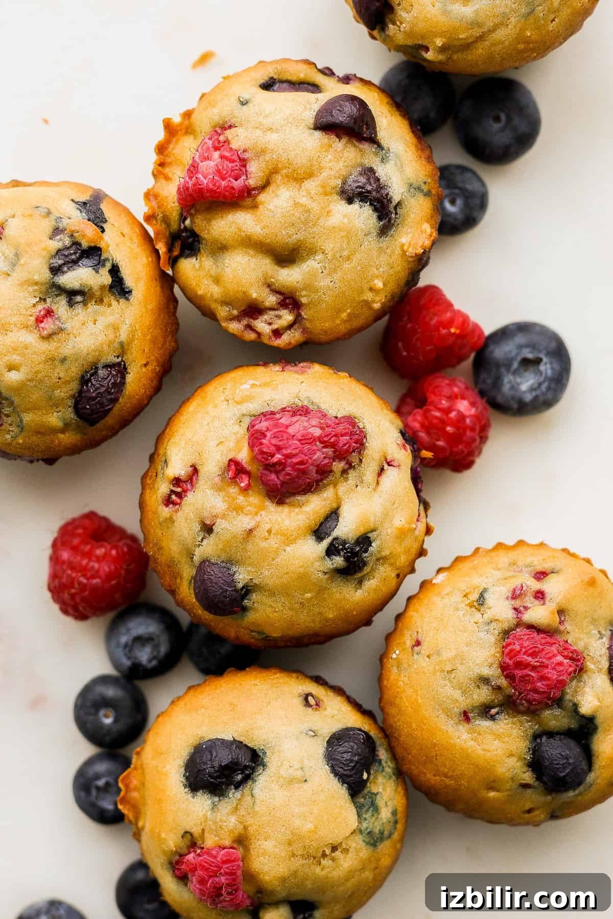 Greek Yogurt Berry Muffins with Mixed Berries 2 A group of muffins with raspberries and blueberries on top.