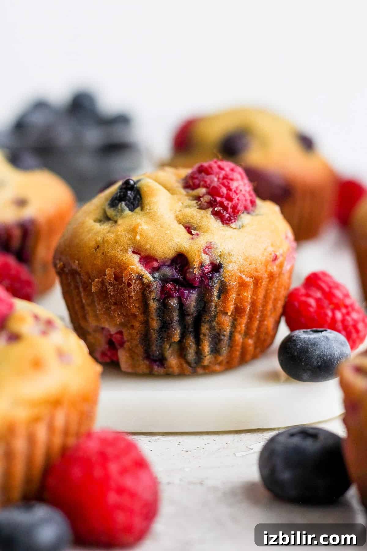 Greek Yogurt Berry Muffins with Mixed Berries 5 Berry muffins with blueberries and raspberries on a cutting board.