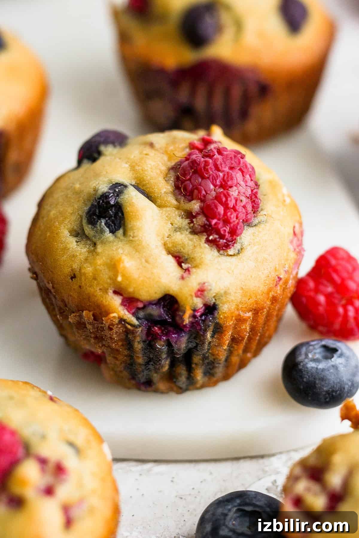 Greek Yogurt Berry Muffins with Mixed Berries 6 Berry muffins with blueberries and raspberries on a white plate.