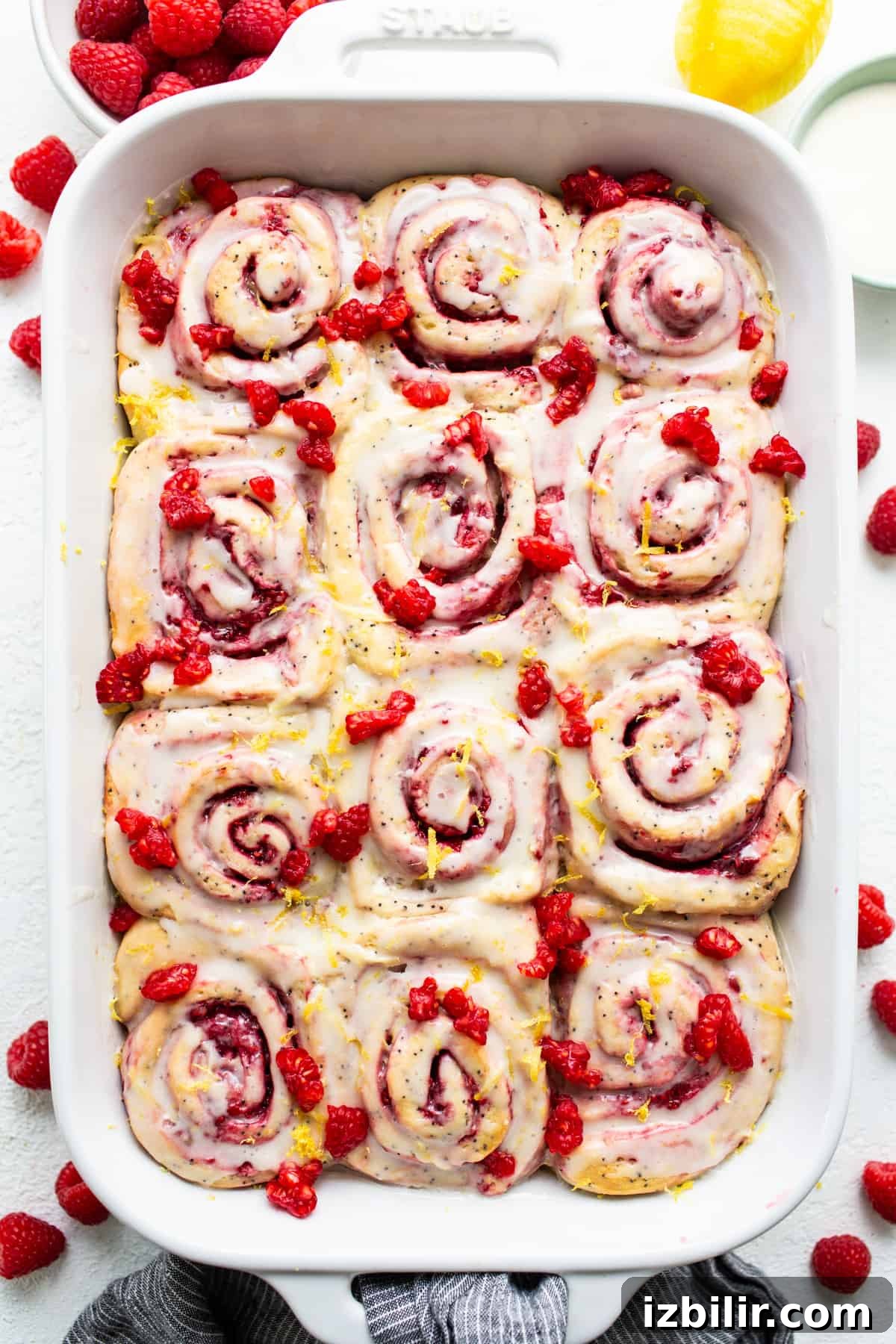 Raspberry cinnamon rolls in a white baking dish.