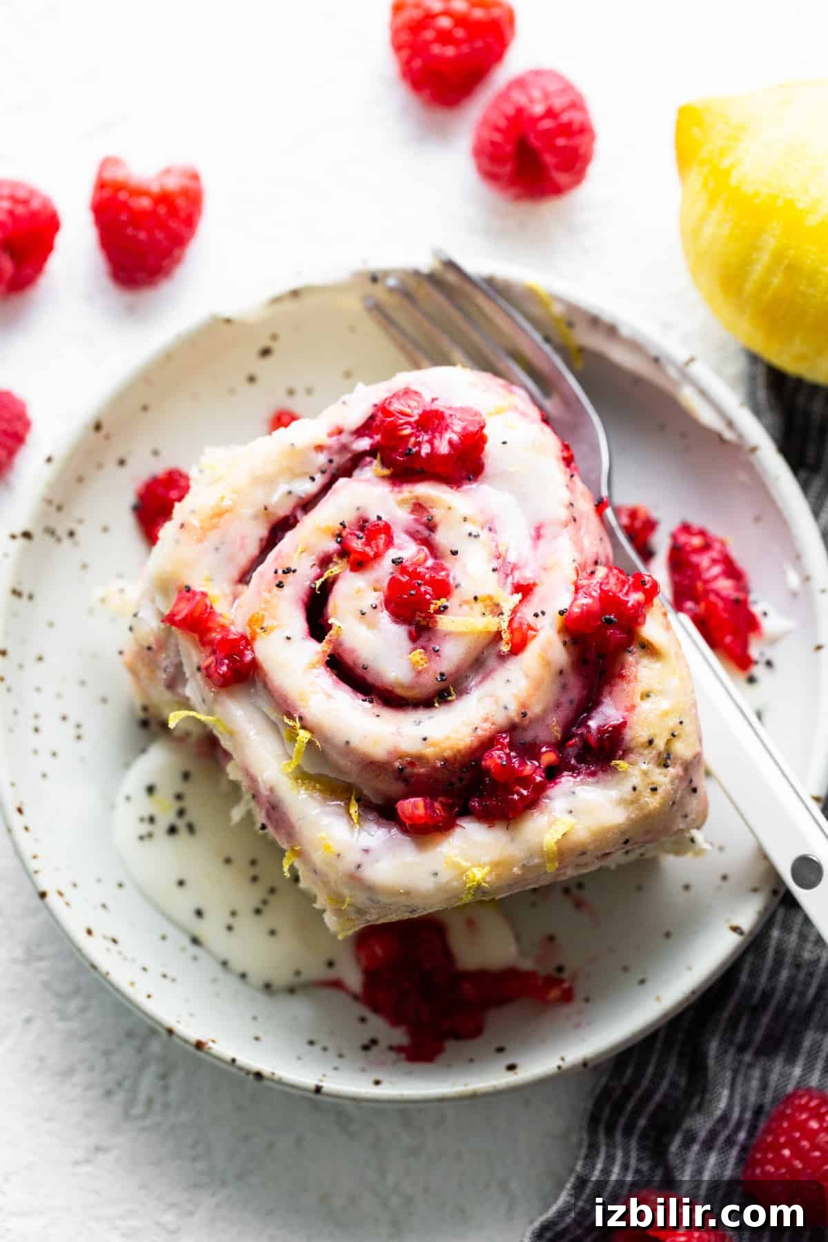 A plate with a raspberry roll and a fork.