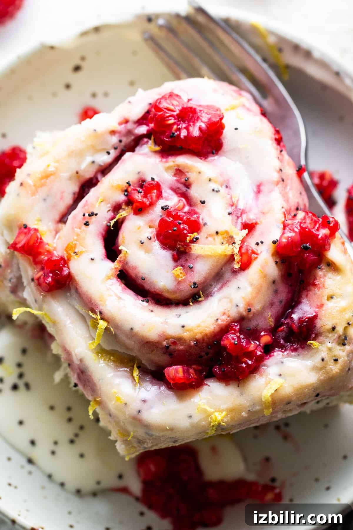 A slice of raspberry roll with a fork on a plate.