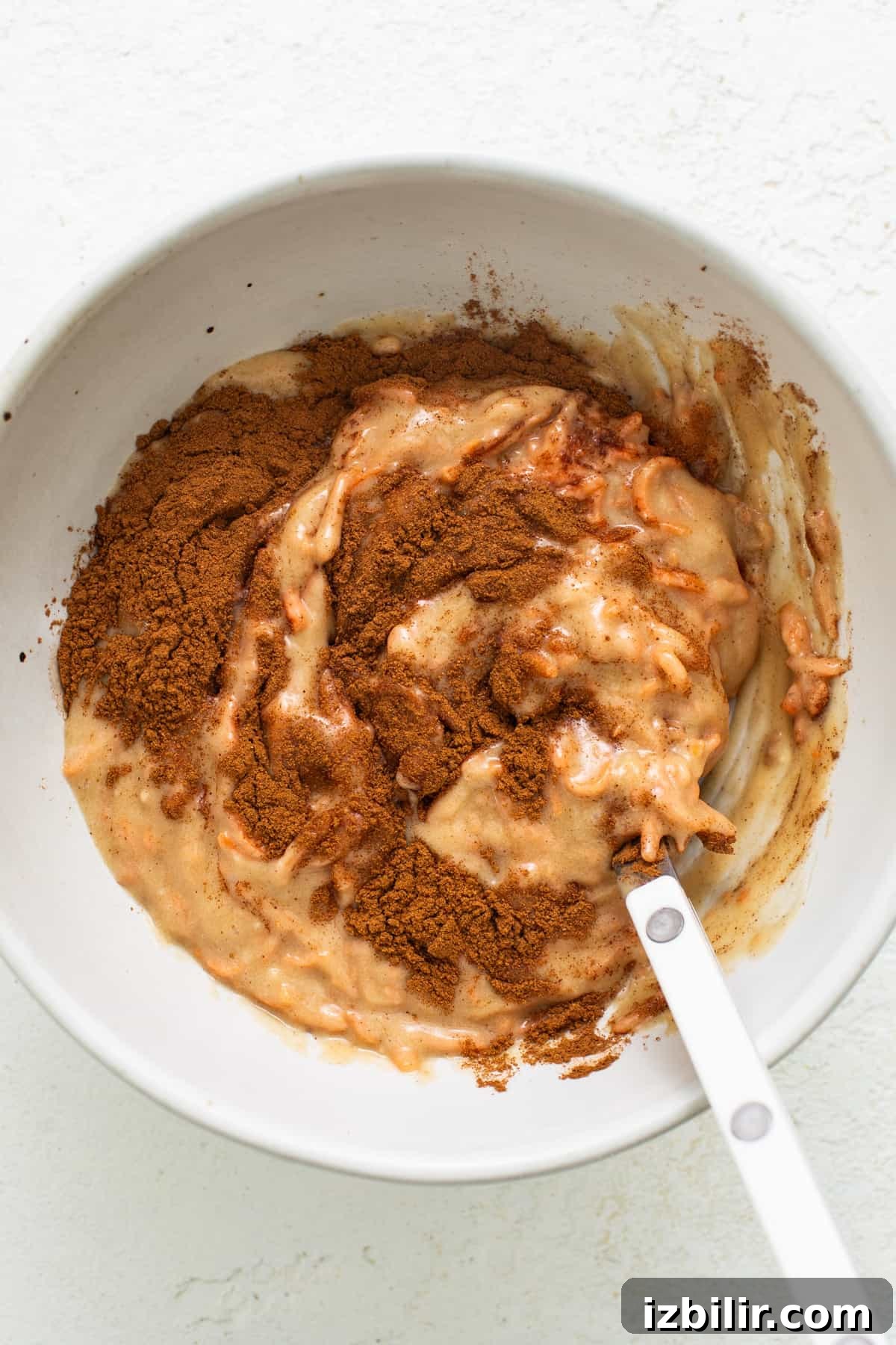 Spiced Carrot Coffee Cake with Cream Cheese Glaze 3 A white bowl with a spoon in it.