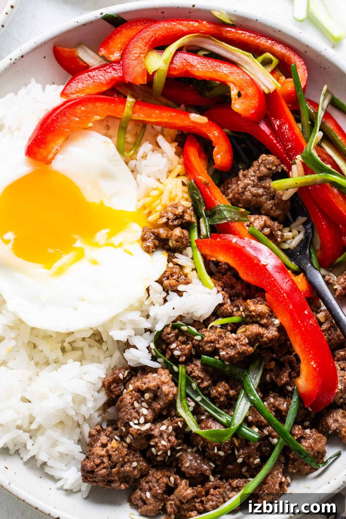 Bibimbap with Korean ground beef, vegetables, and a sunny-side-up egg in a bowl.