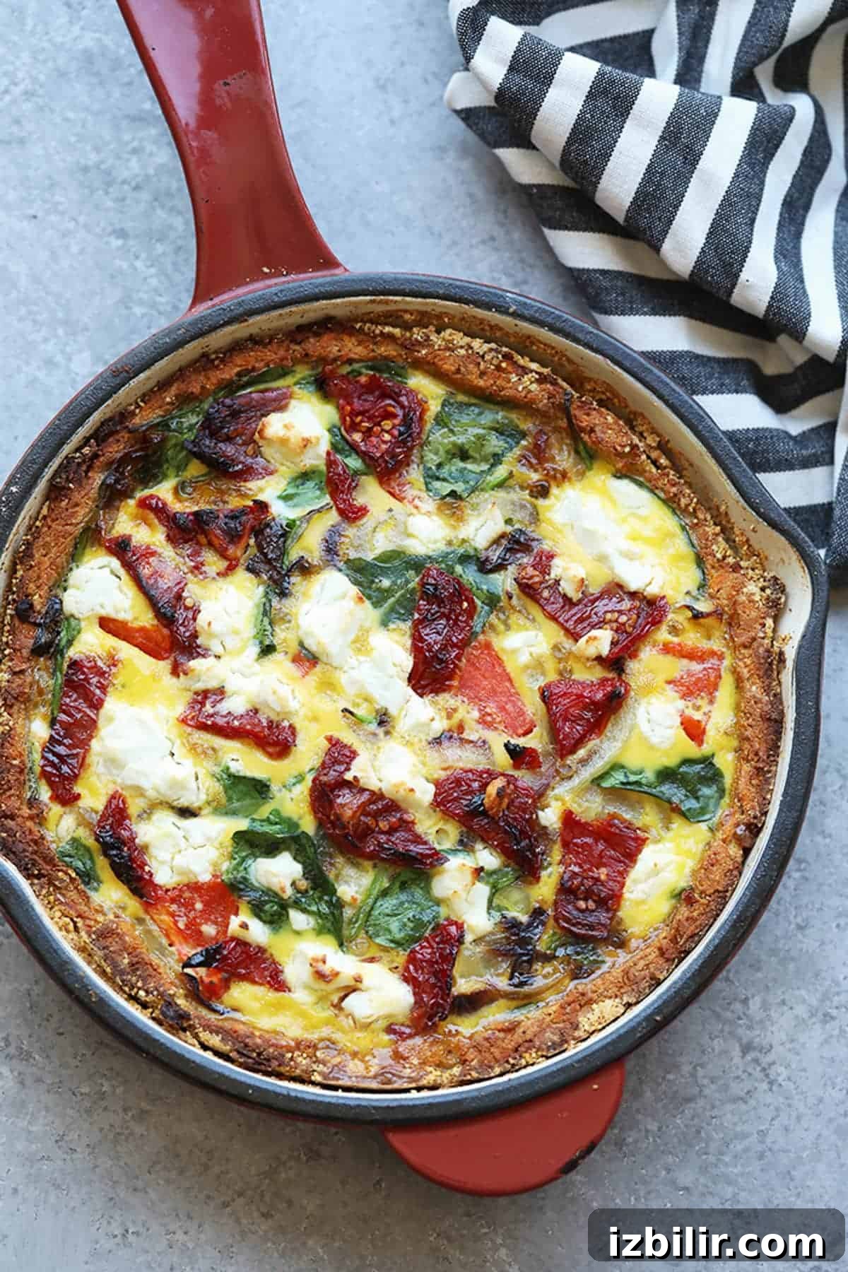 a quiche with spinach and tomatoes in a skillet.