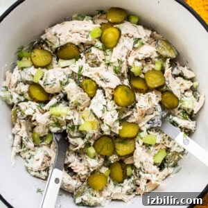 Bowl of tuna salad with pickles and herbs.