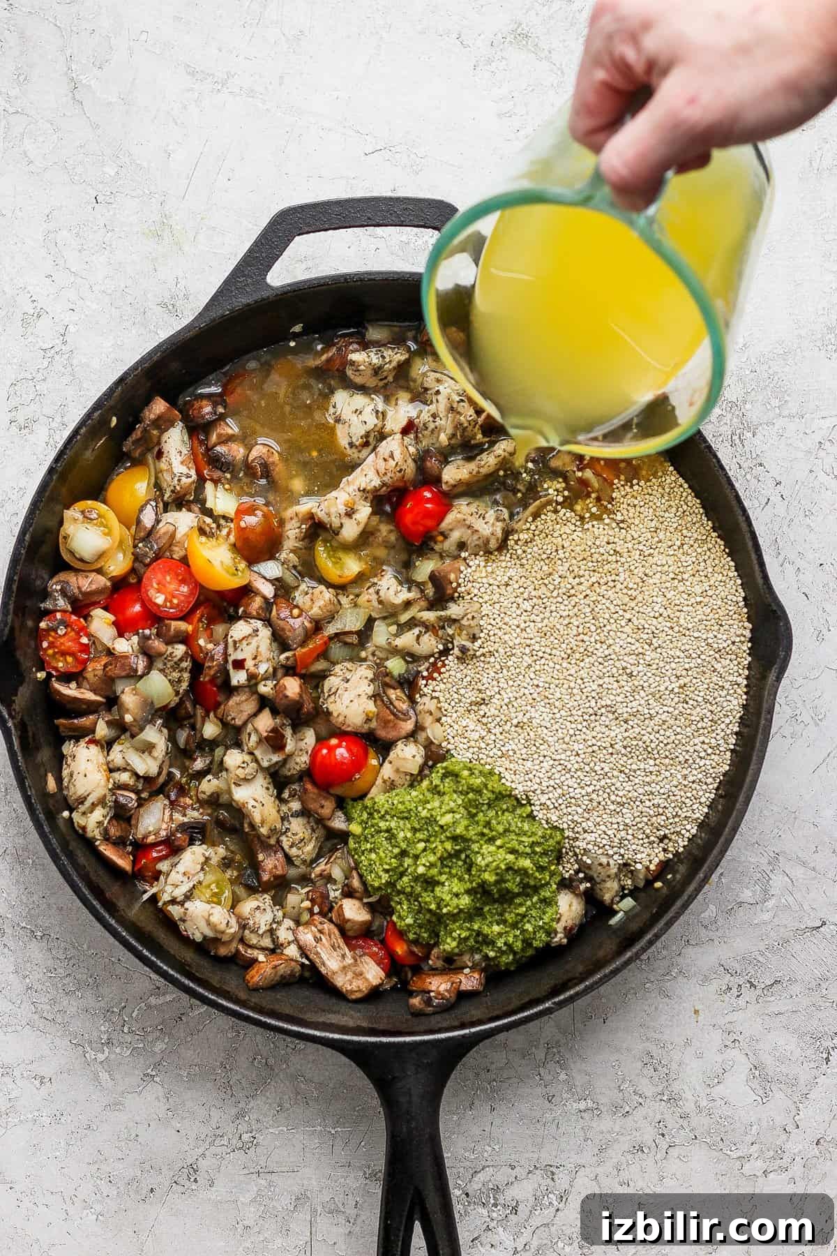 One-Pot Pesto Chicken and Quinoa Skillet Recipe 6 A person pouring olive oil into a skillet.