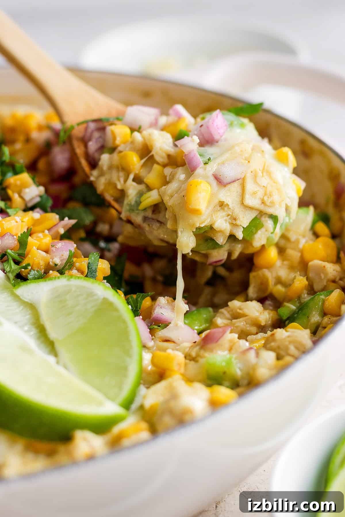 Mexican corn tortillas in a pan with a wooden spoon.