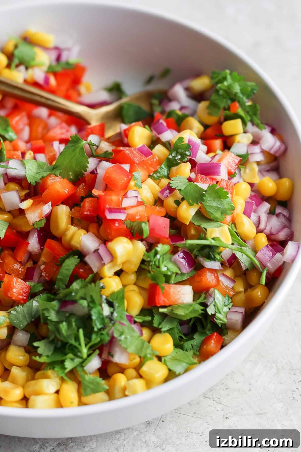Crispy Chicken Tacos with Cotija Cheese and Lime 4 A vibrant bowl of corn salsa with diced red onions, chopped tomatoes, and fresh cilantro.