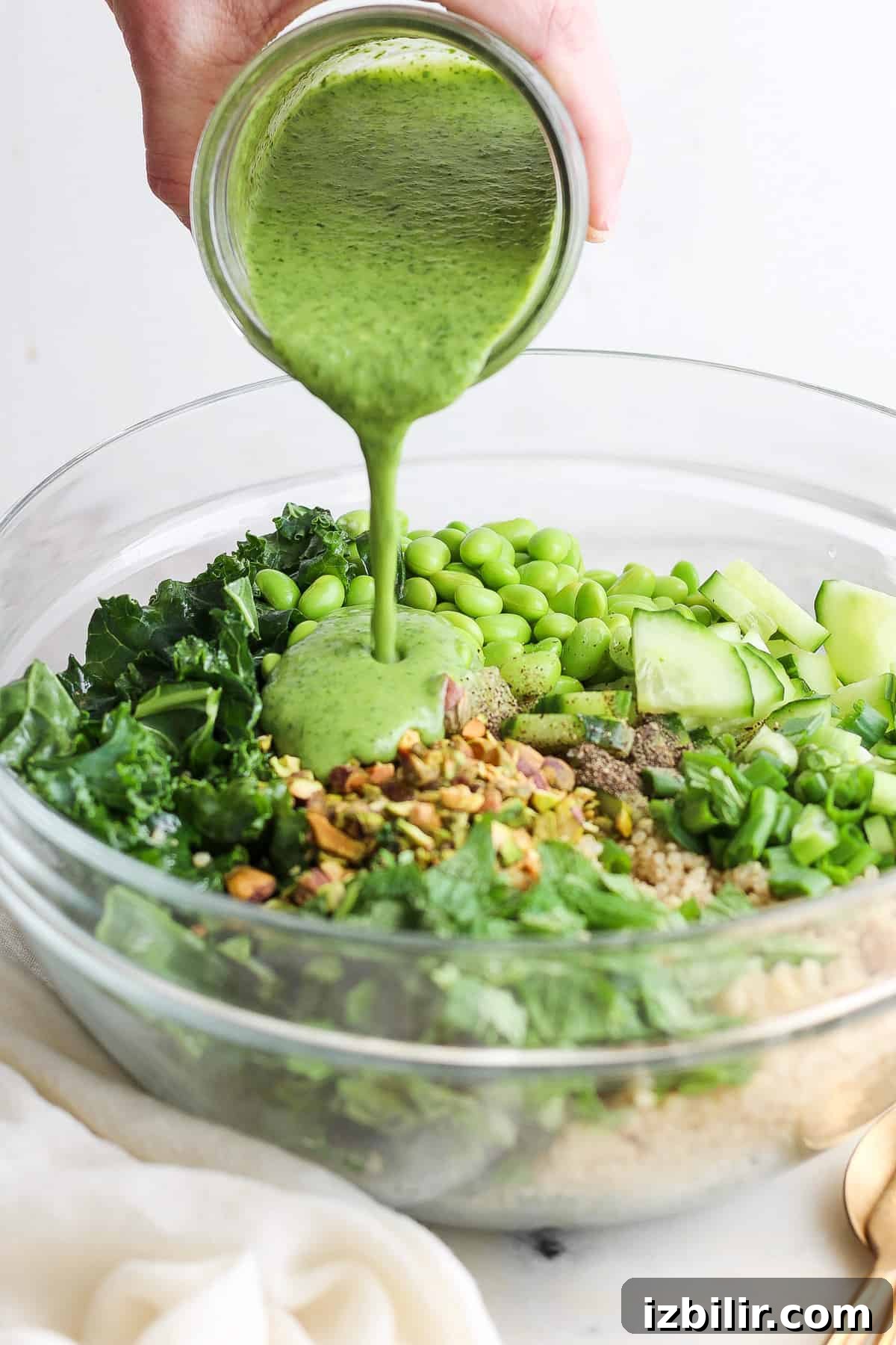 Creamy Green Goddess Quinoa Salad with Avocado and Herb Dressing 4 Pouring green goddess dressing over quinoa and kale salad