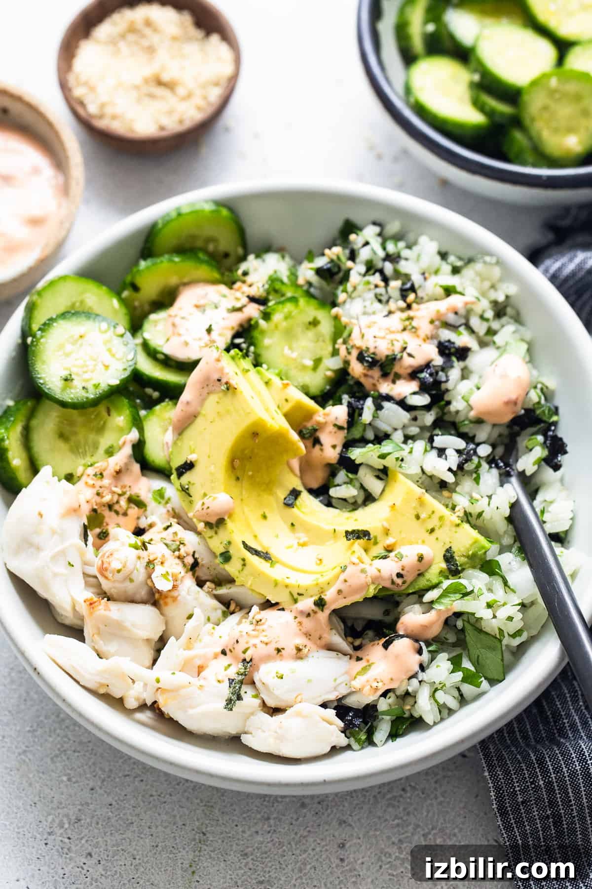 A white bowl with a bowl of rice and cucumbers.