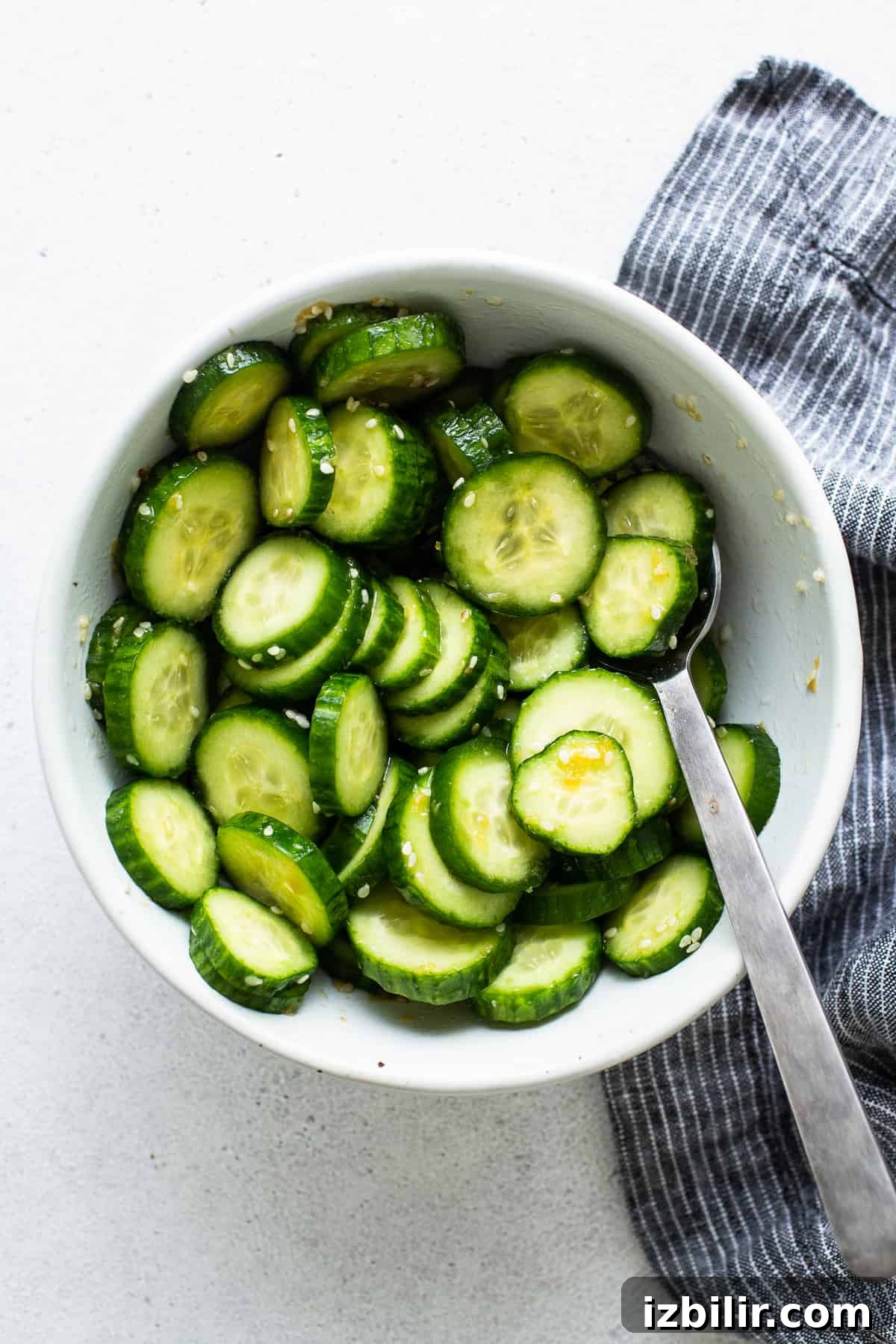 Cucumbers in a white bowl with a spoon.