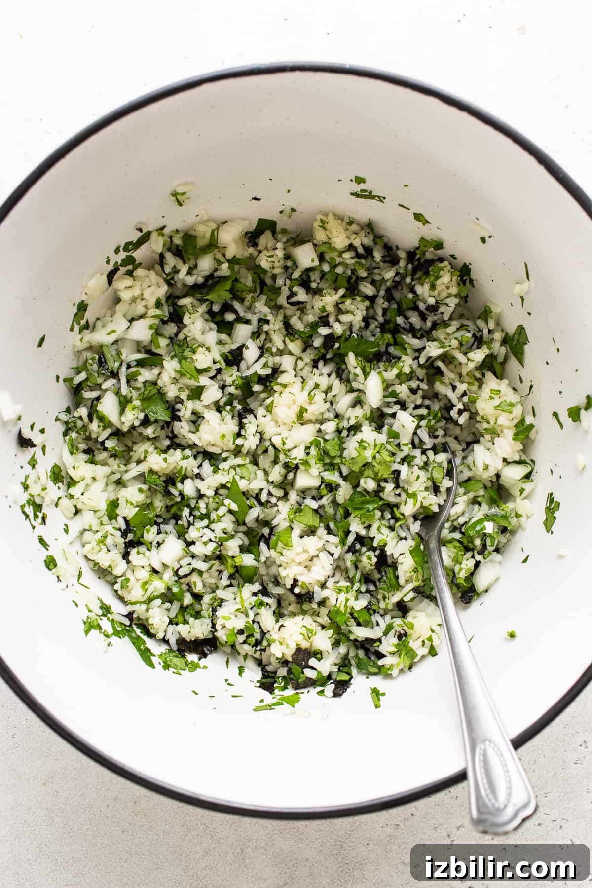 A white bowl filled with greens and a spoon.