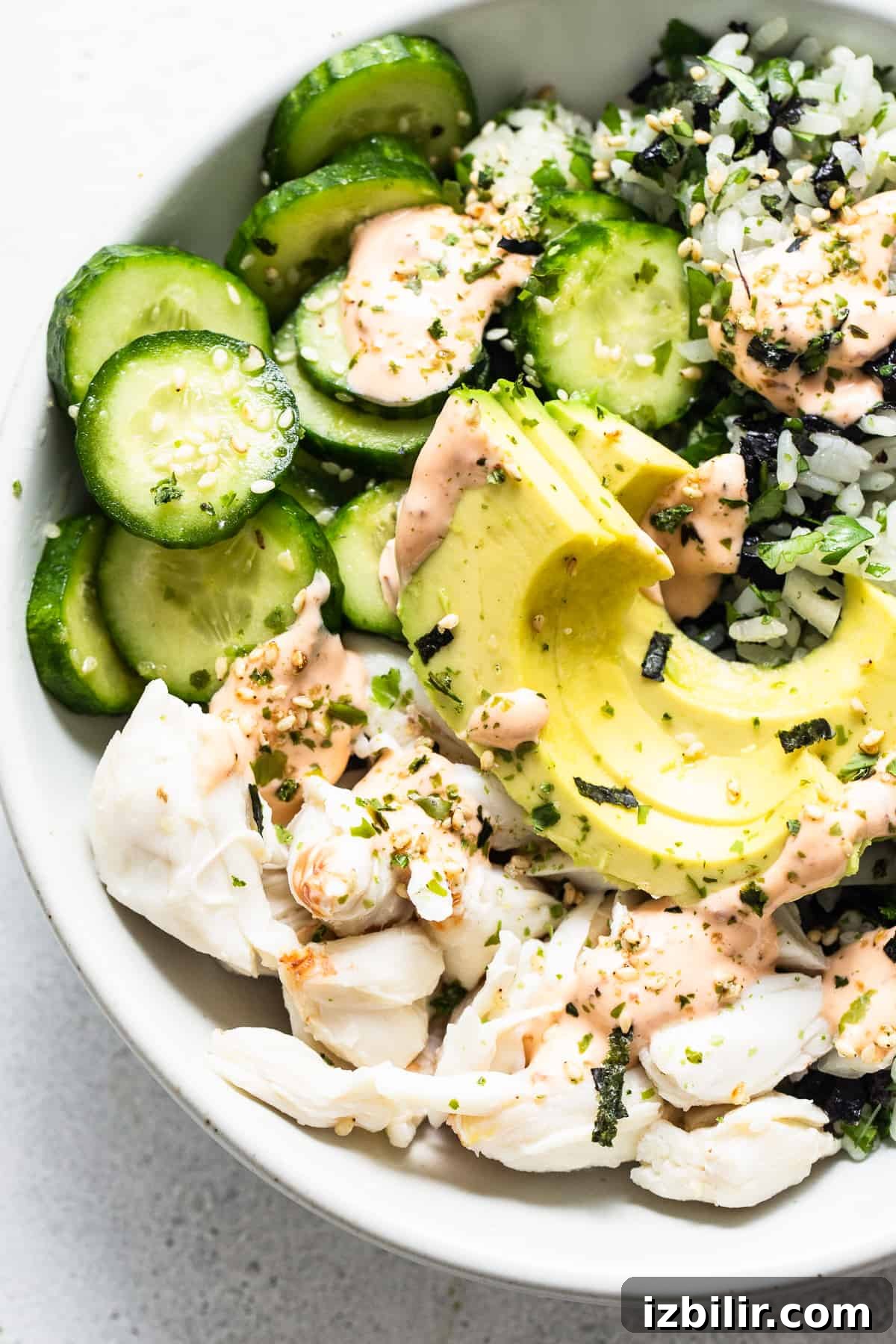 A bowl of sushi with cucumbers and avocado.