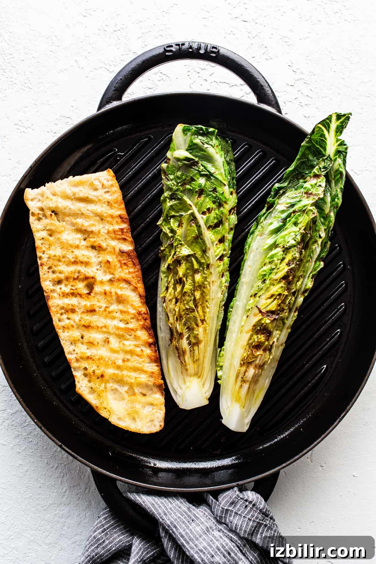 Grilled fish fillet and halves of romaine lettuce on a stove-top grill pan.