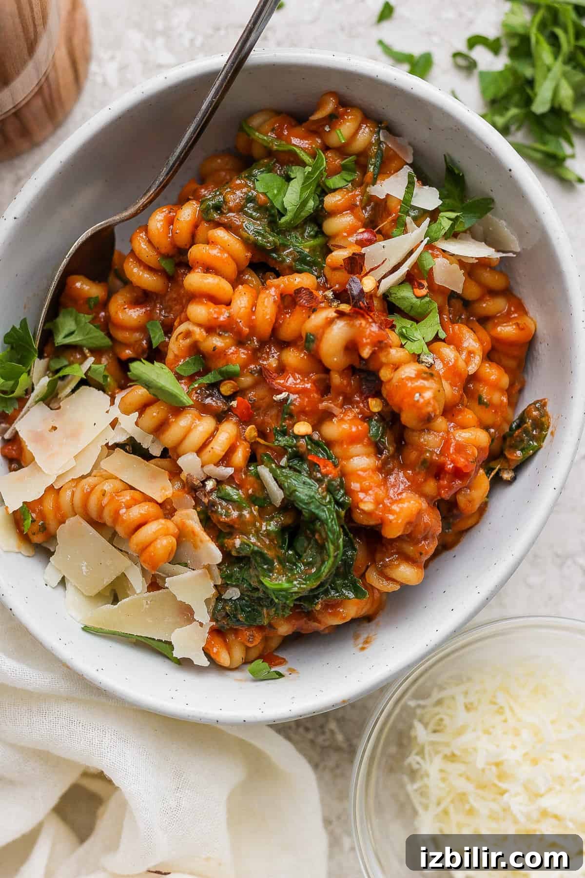 Creamy One-Pot Vodka Pasta Recipe 2 Bowl of tomato-based pasta with spinach and shaved parmesan cheese.