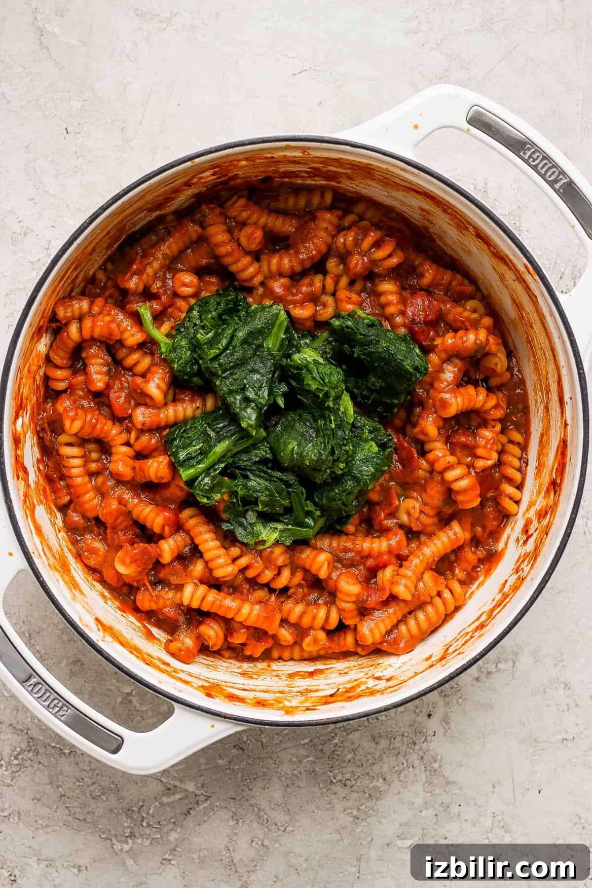 Creamy One-Pot Vodka Pasta Recipe 5 Pasta with tomato sauce and spinach in a white pot.