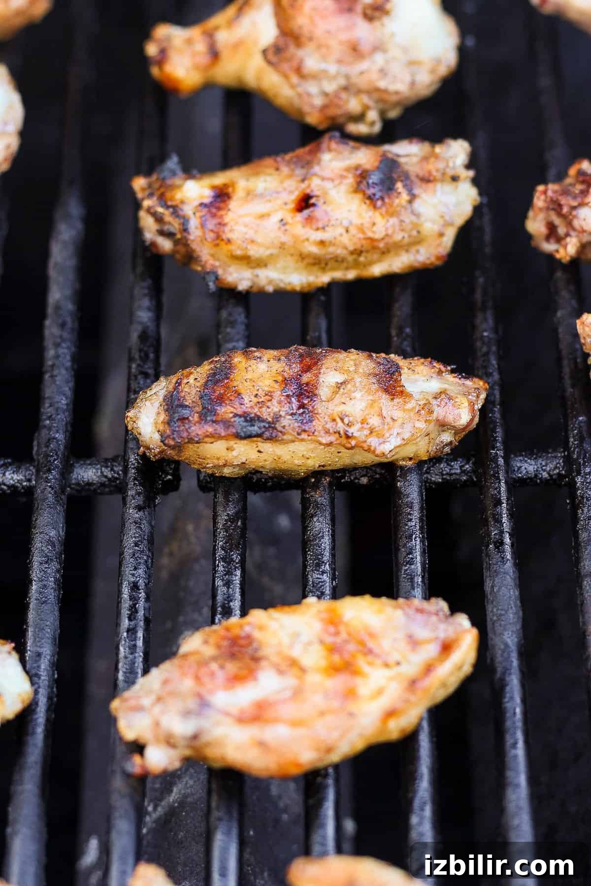Grilled chicken wings on a barbecue grill with grill marks visible.