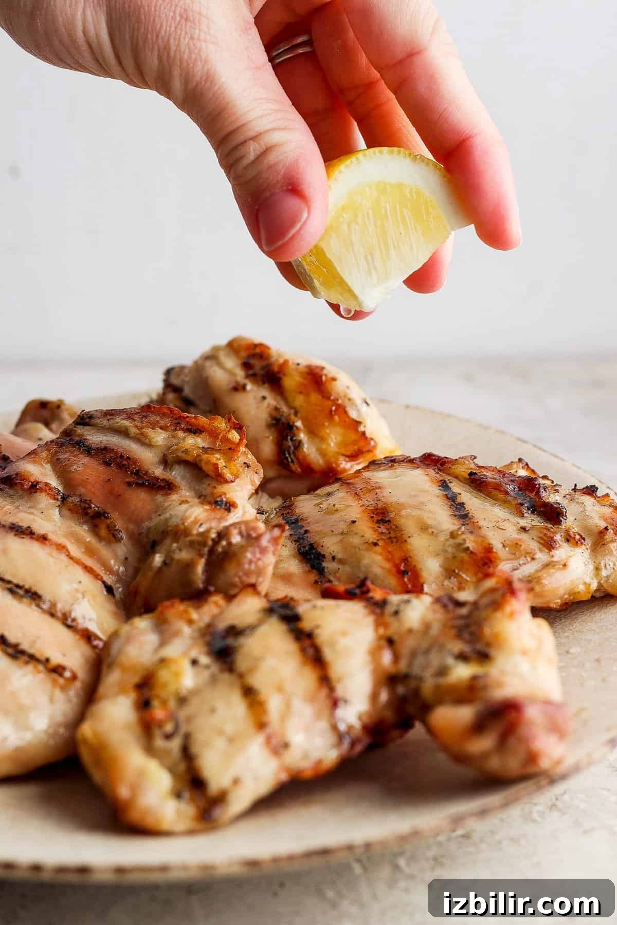 Squeezing lemon juice over grilled chicken breasts.