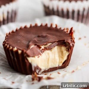 A close-up of a peanut butter cup with a bite taken out, revealing creamy peanut butter filling and a thick chocolate shell.