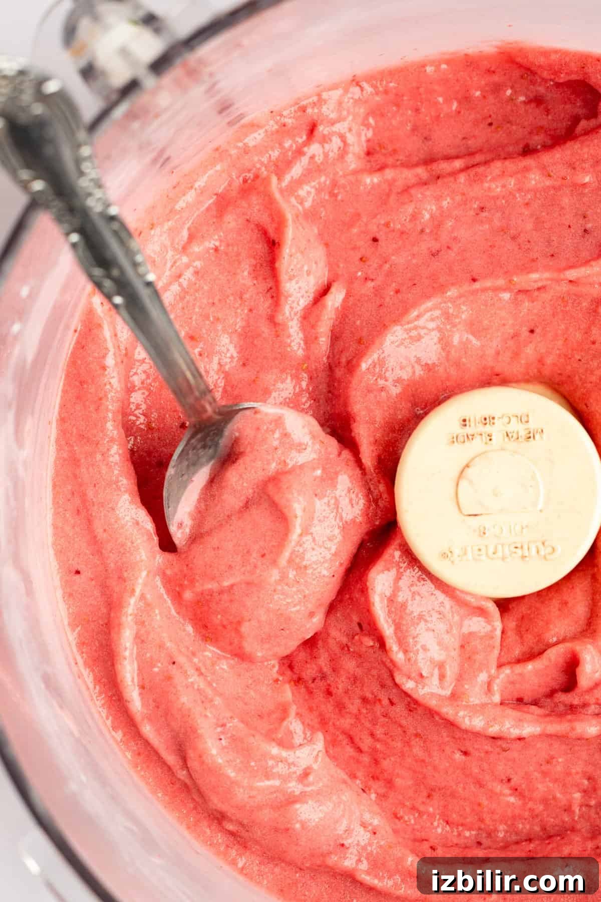 How to Make Strawberry Dole Whip: Dairy Free Soft Serve 5 Top-down view of a bowl of fresh strawberry puree with a measuring spoon dipped inside.