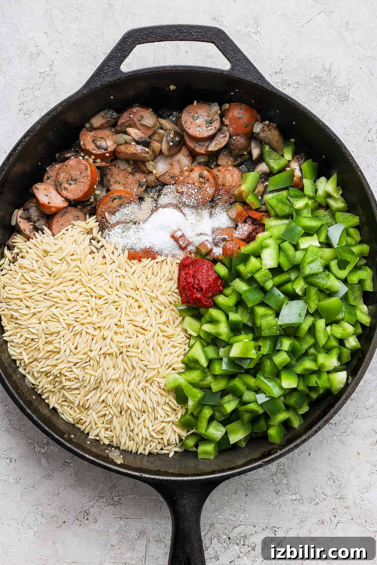 A frying pan with rice, mushrooms and green peppers.