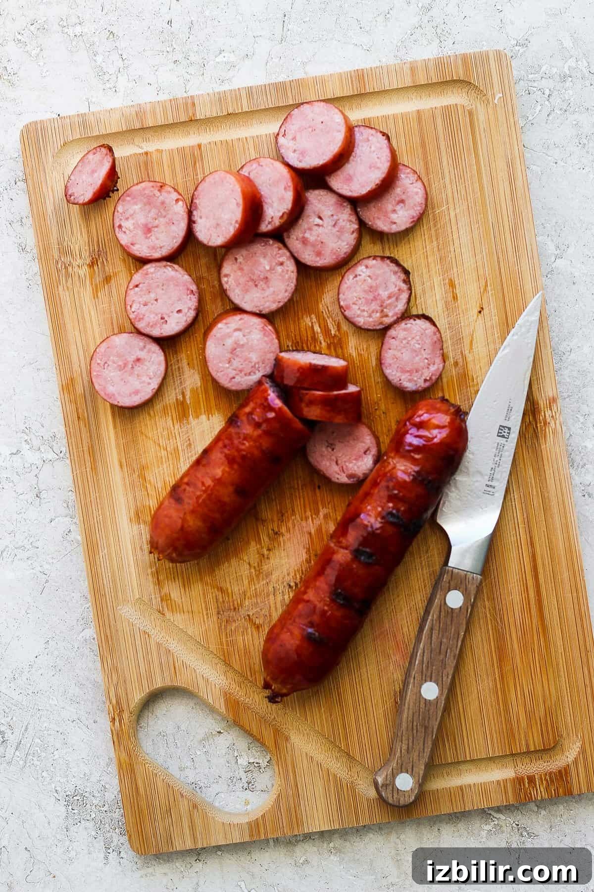 Savory Mixed Protein Bowl with Grains and Veggies 3 Sliced sausage on a wooden cutting board with a knife.