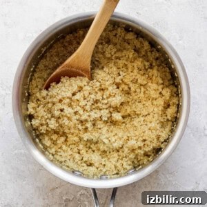 Savory Mixed Protein Bowl with Grains and Veggies 8 Cooked quinoa in a pot with a wooden spoon.