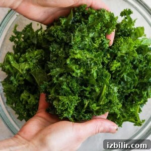 Savory Mixed Protein Bowl with Grains and Veggies 9 Hands holding fresh kale above a glass bowl.