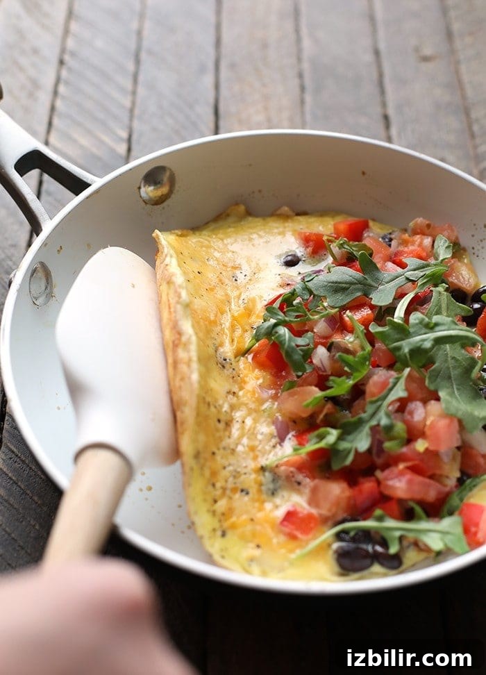 veggie omelette being folded over in skillet